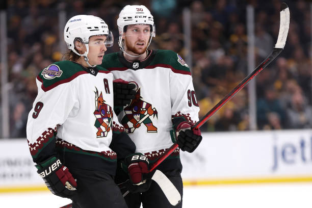 BOSTON, MASSACHUSETTS - OCTOBER 15: Clayton Keller #9 of the Arizona Coyotes celebrates with J.J. Moser #90 after scoring a goal against the Boston Bruins  during the second period at TD Garden on October 15, 2022 in Boston, Massachusetts. (Photo by Maddie Meyer/Getty Images)